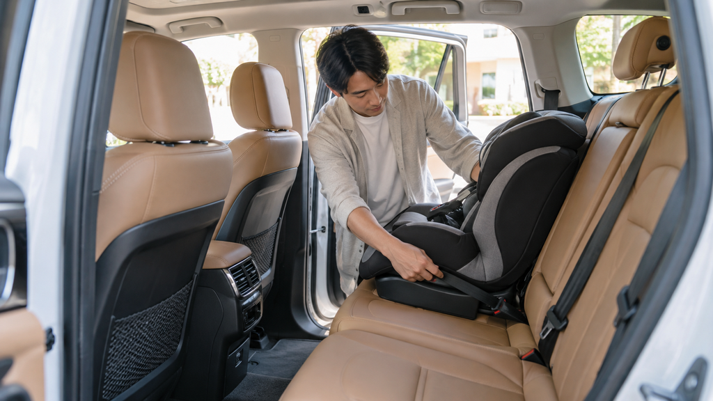 SUVの後席にチャイルドシートを取り付ける父親